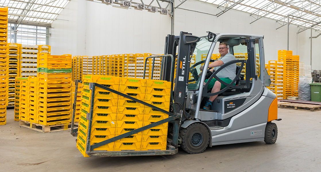 Collega op een heftruck met gele kisten met groenteproducten