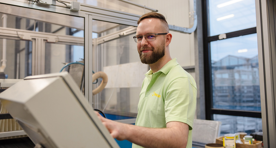 Collega bij een machine met de hand op de bedieningsknoppen.